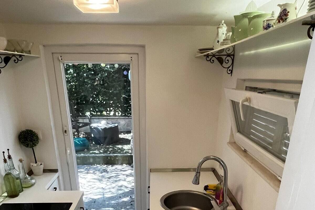 A compact kitchen with a sink, a small stove, and a window overlooking a snowy outdoor area.