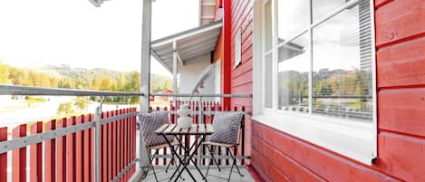 Ein Balkon mit roter Holzverkleidung, weißem Geländer und einem Tisch mit Stühlen.