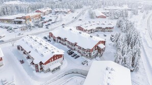A snow-covered building with multiple parking spaces and a road leading to it. - Modern 1BR Apartment next to Ski Slopes (Sirkka)