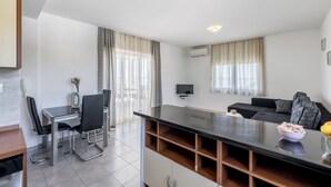 A modern living room with a black sofa, a coffee table, and a TV mounted on the wall. - Casa Di Tenor (Stobreč)
