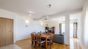 A modern living space with a dining area, a grey sofa, and a TV. - Casa Di Tenor (Stobreč)