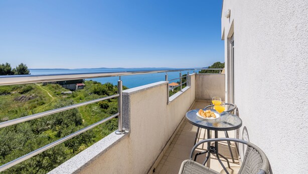 A balcony with a table and chairs, overlooking a coastal view. - Casa Di Tenor (Stobreč)