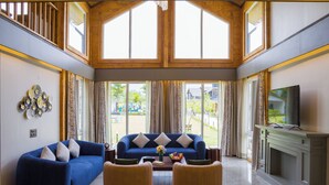 A spacious living room with a blue sofa, two armchairs, a fireplace, and a television. - ELIVAAS Esh Birch  (Palampur)