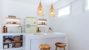 A modern kitchen with a central island, wooden stools, and pendant lighting.