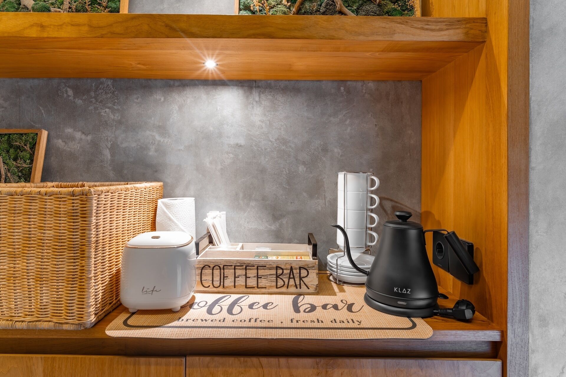 Un coin café aménagé avec une machine à café, une bouilloire, un panier et un panneau indiquant : « Café fraîchement préparé, servi tous les jours. »