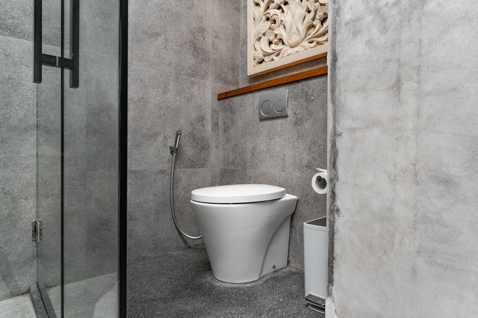 A modern bathroom with a shower, toilet, and a decorative panel above the toilet.