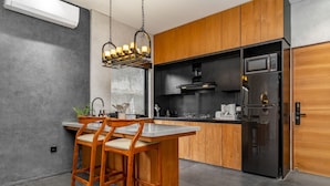 Una cocina moderna con armarios de madera, un refrigerador negro y una zona de bar.