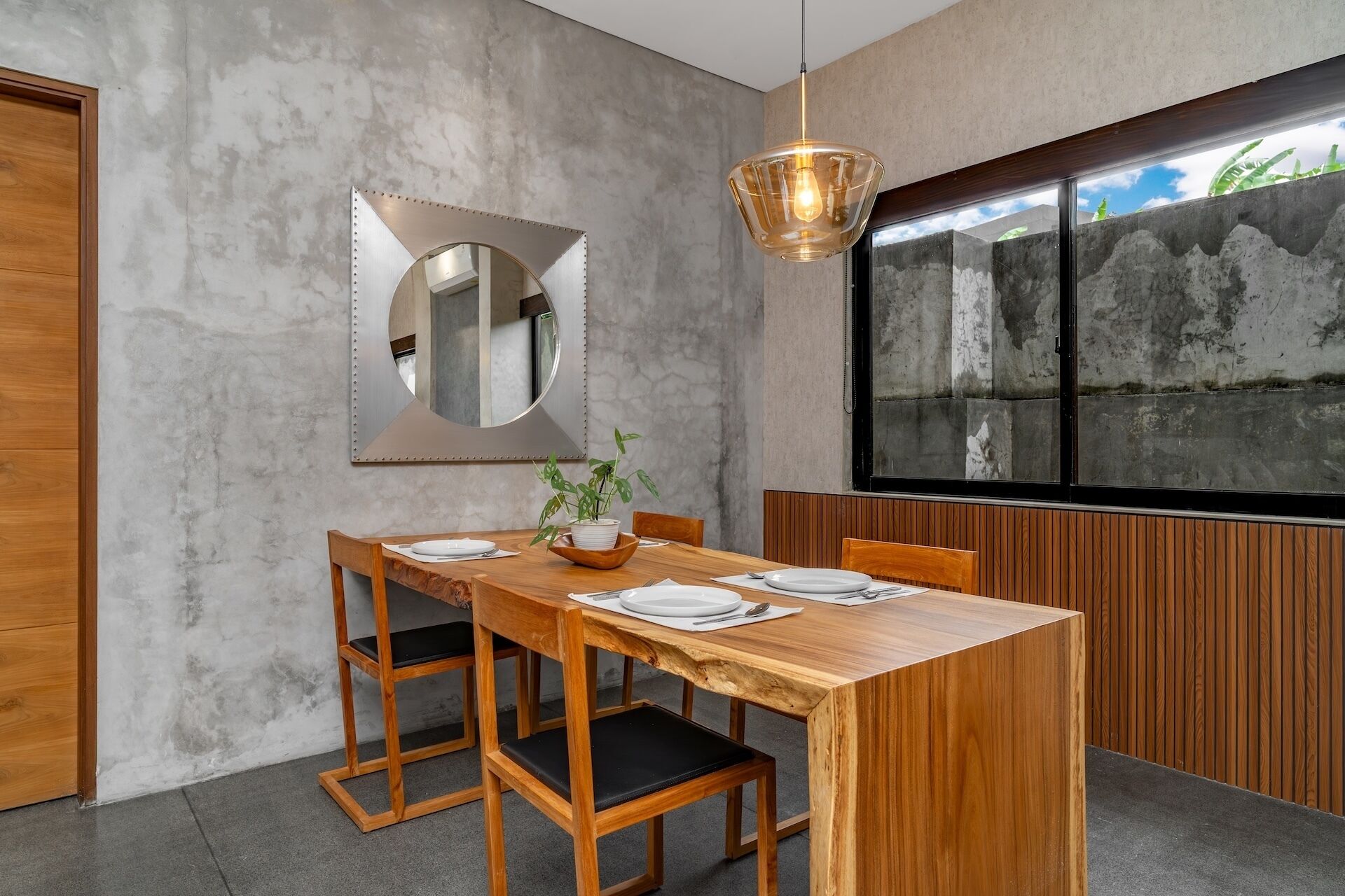Un comedor moderno con una mesa de madera, sillas y un espejo grande.