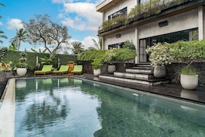 Una piscina al aire libre, sillones reclinables de piscina