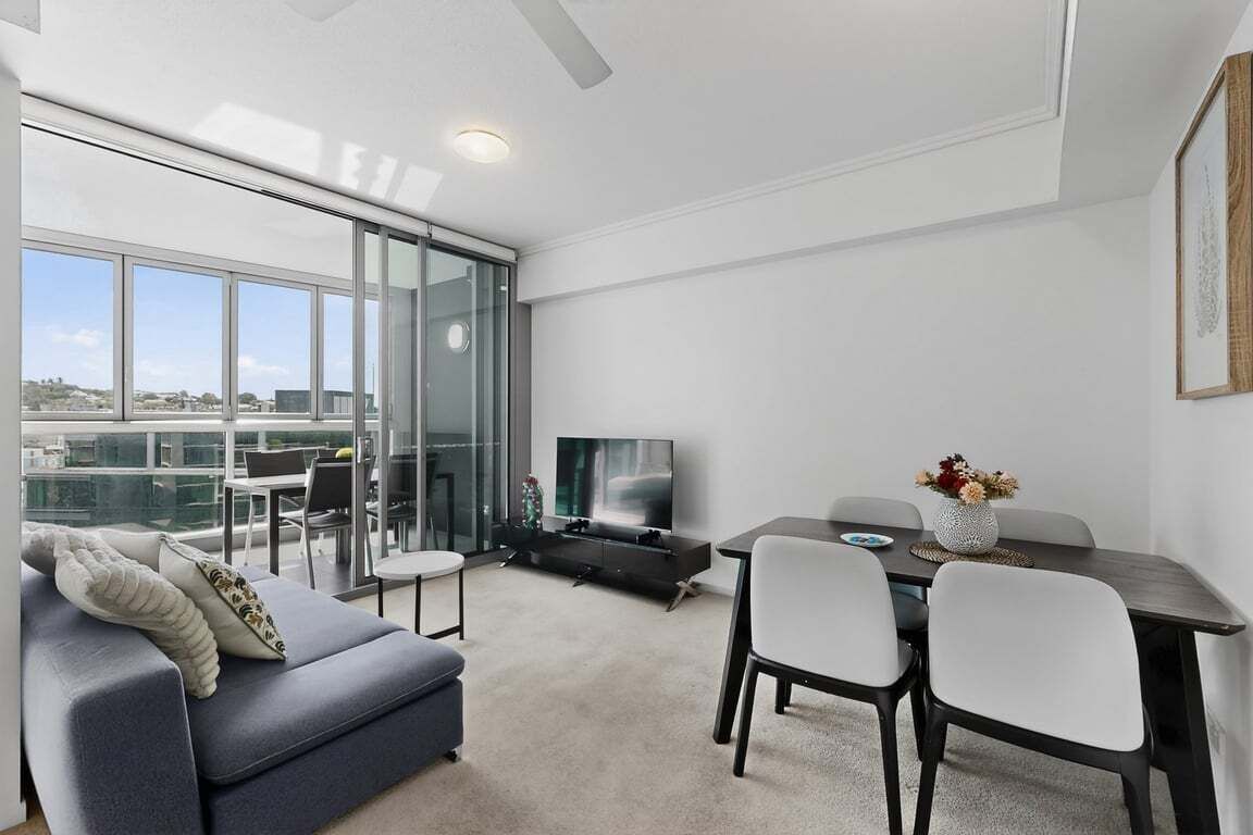 A modern living room with a sofa, TV, dining table, and chairs.