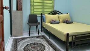 A bedroom with a bed, a chair, a wooden wardrobe, and a window with blinds. - Homestay Adilah D (Selising)