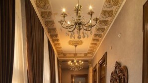 A hallway with a red carpet, a chandelier, a mirror, and a fire extinguisher. - Nizami Boutique Hotel (Baku)