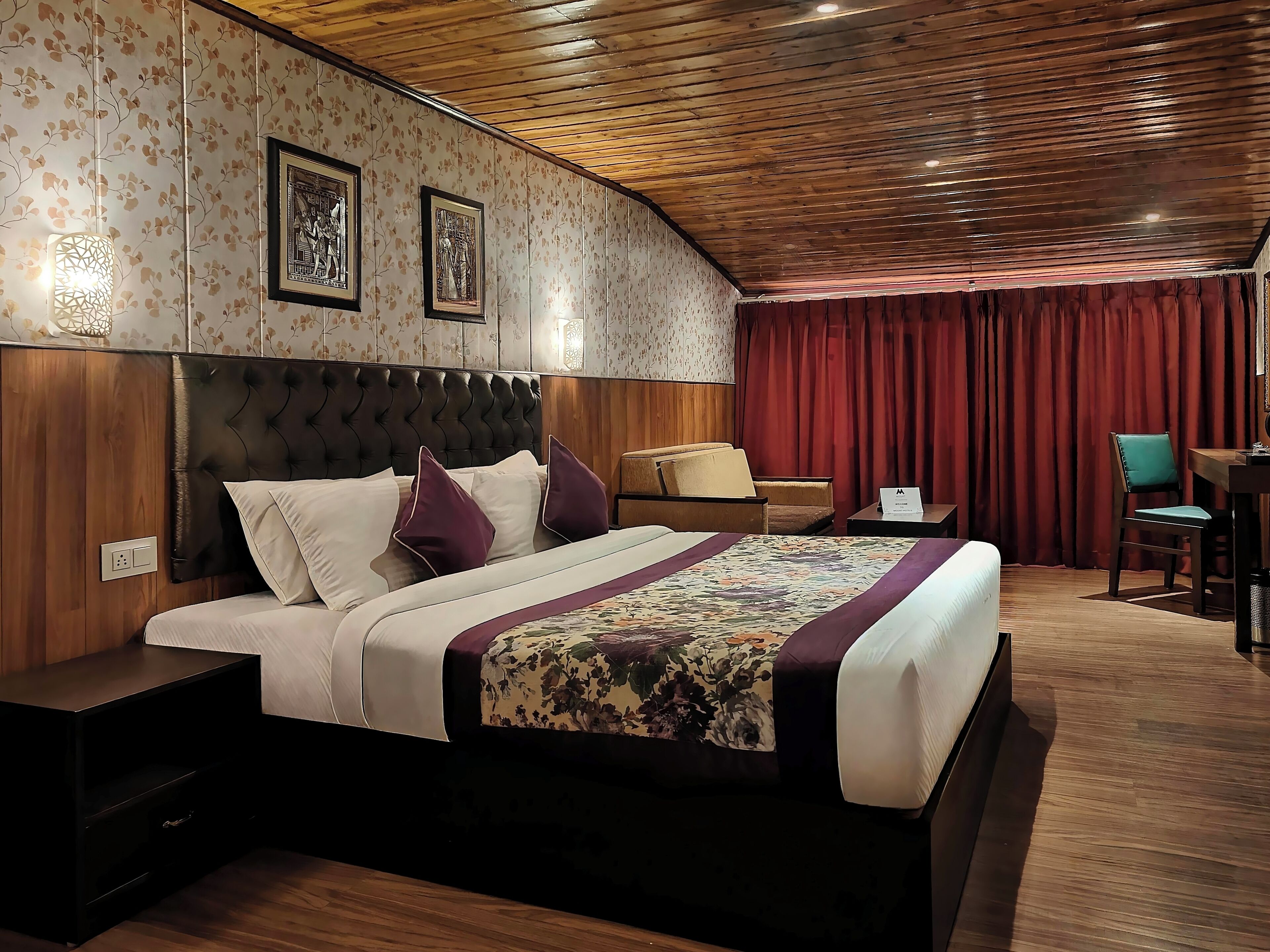 A hotel room with a bed, a nightstand, a desk, and a chair.