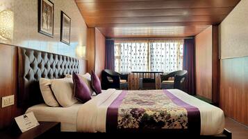 A hotel room with a large bed, a small table, and two chairs.