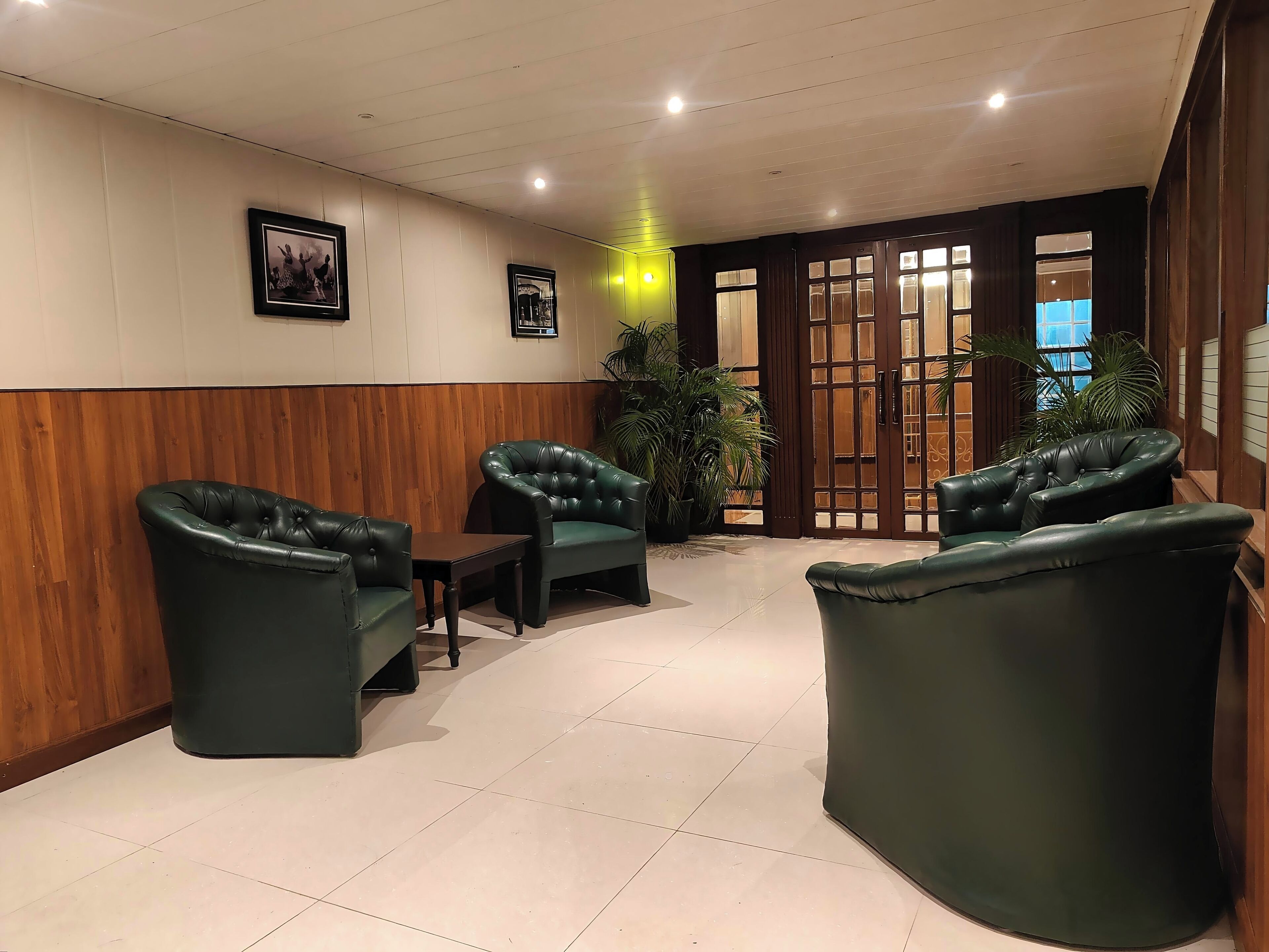 Eine Lobby mit Ledersesseln, einem kleinen Tisch und einer Holzwand.