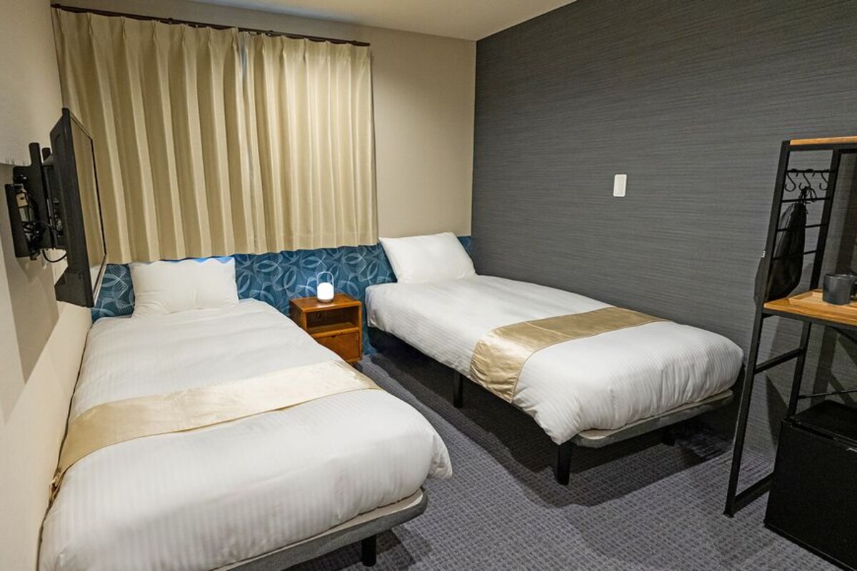 A hotel room with two beds, a nightstand, a TV, and a mirror.