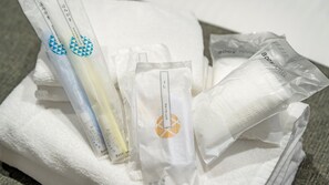 Una pila de toallas blancas y artículos de aseo, incluyendo cepillo de dientes, peine y toalla para bebé.