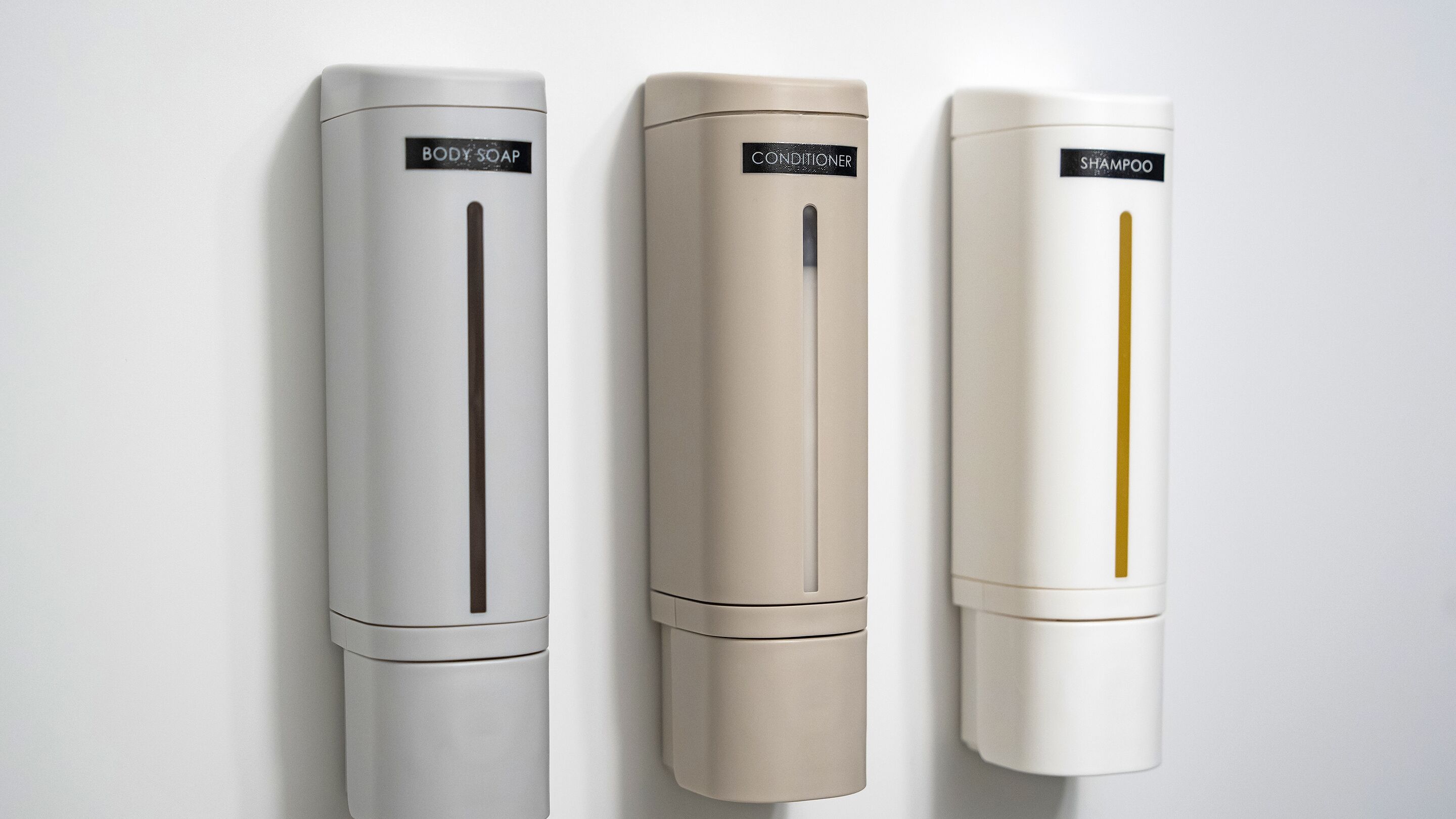 Three wall-mounted dispensers labeled BODY SOAP, CONDITIONER, and SHAMPOO.