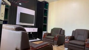 A modern living room with a flat-screen TV, leather sofas, and a wooden coffee table. - Gold Rhino Hotel (Enugu)