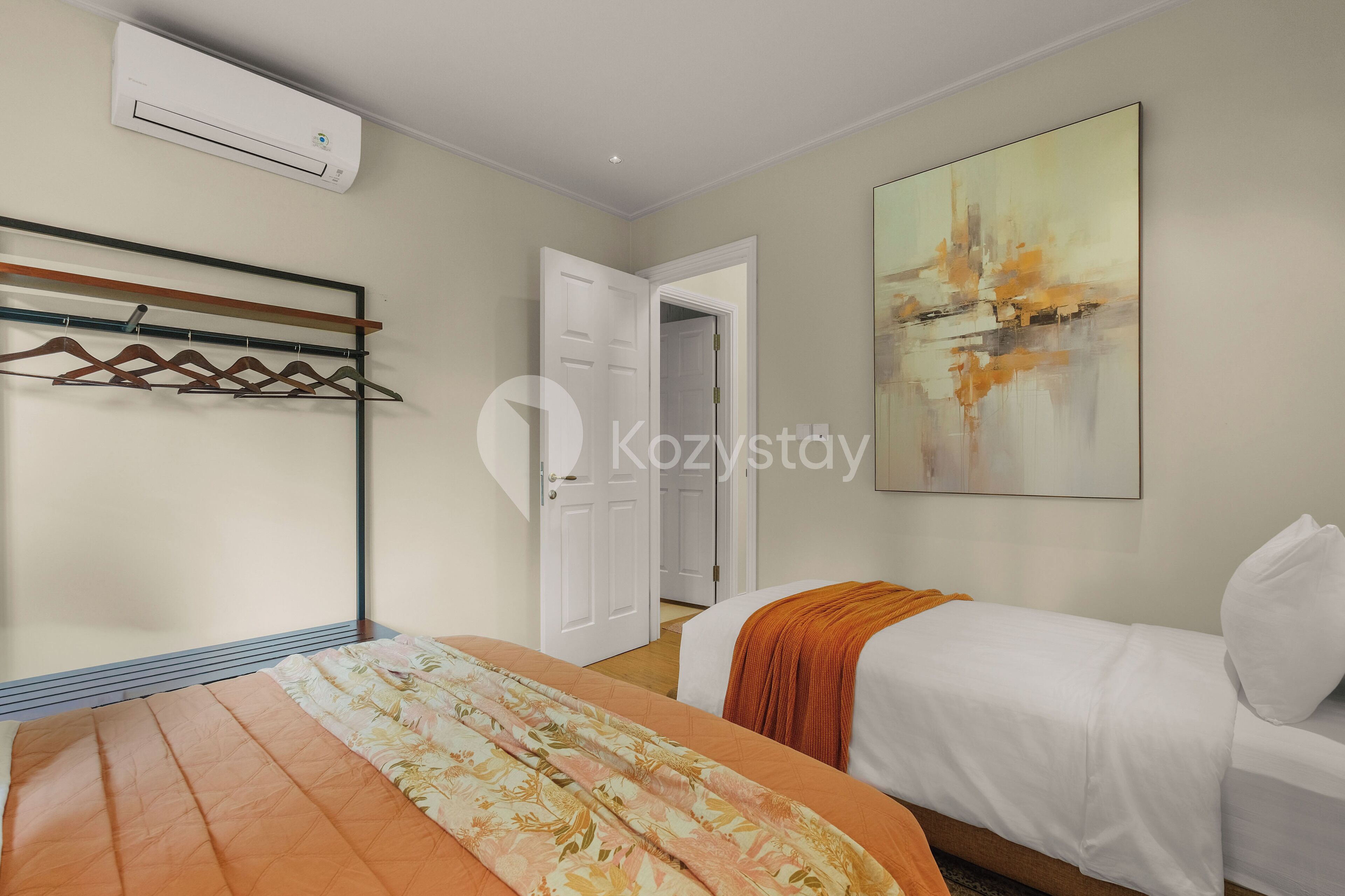 Ein Hotelzimmer mit einem Bett, einem Kleiderhaken, einem Gemälde und einer Klimaanlage.