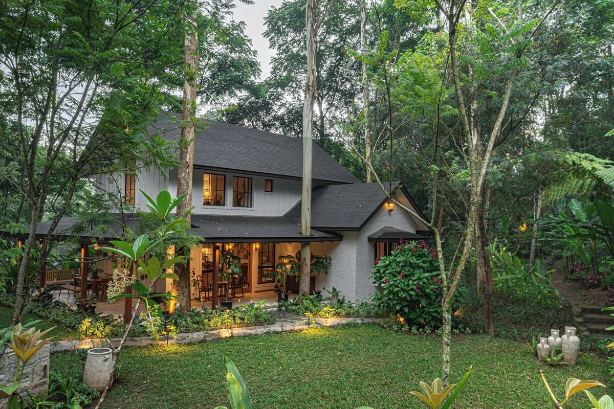 A house surrounded by lush greenery, with a well-maintained garden and a patio area.