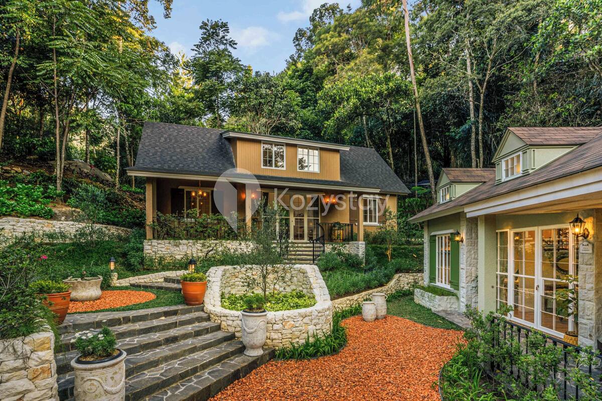 A house with a stone retaining wall, a stone staircase, and a garden with potted plants.