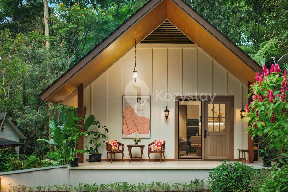 A cozy wooden cabin with a large poster, two chairs, and a small table on the porch, surrounded by lush greenery.