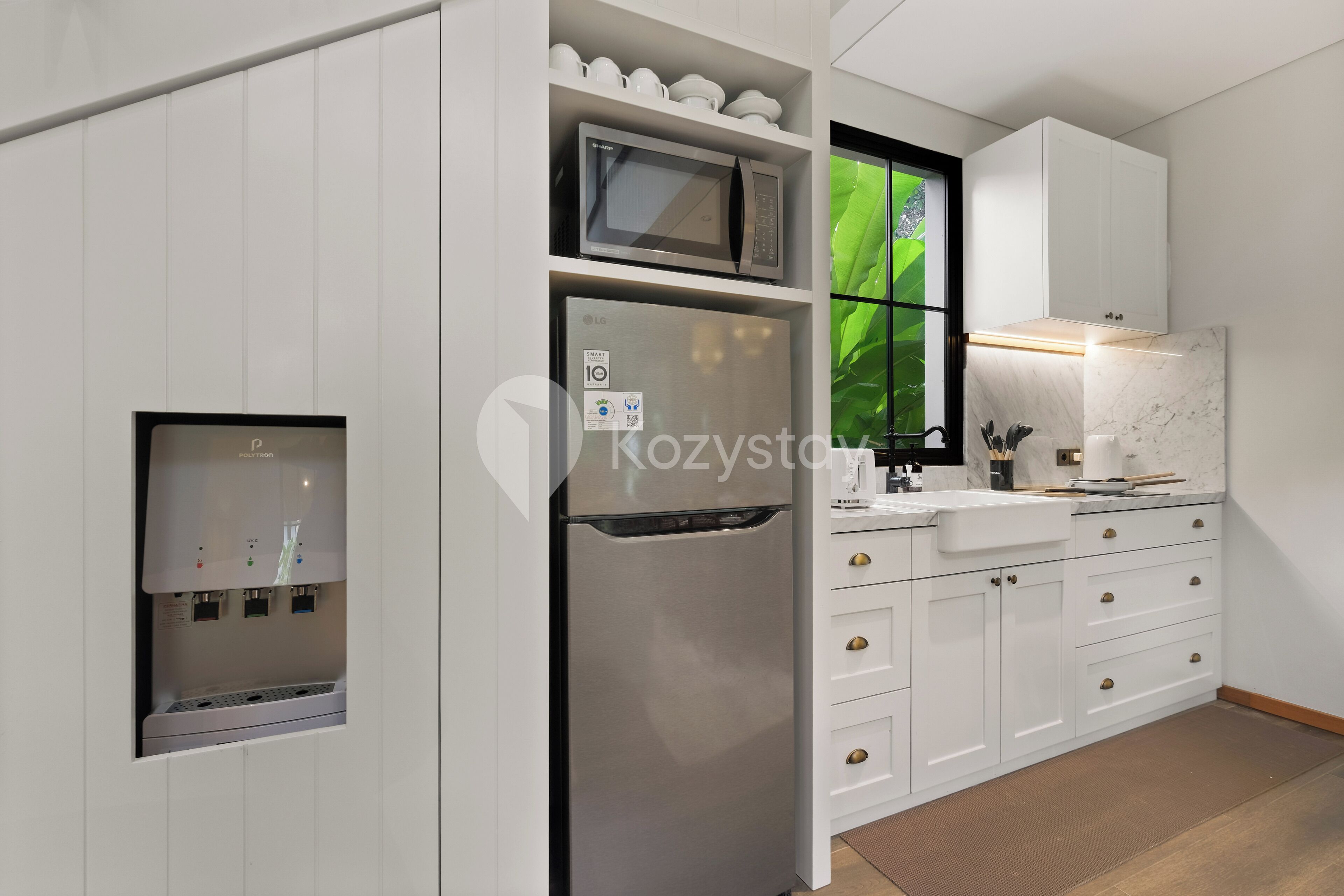 A modern kitchen with white cabinetry, a built-in microwave, a stainless steel refrigerator, and a water dispenser.