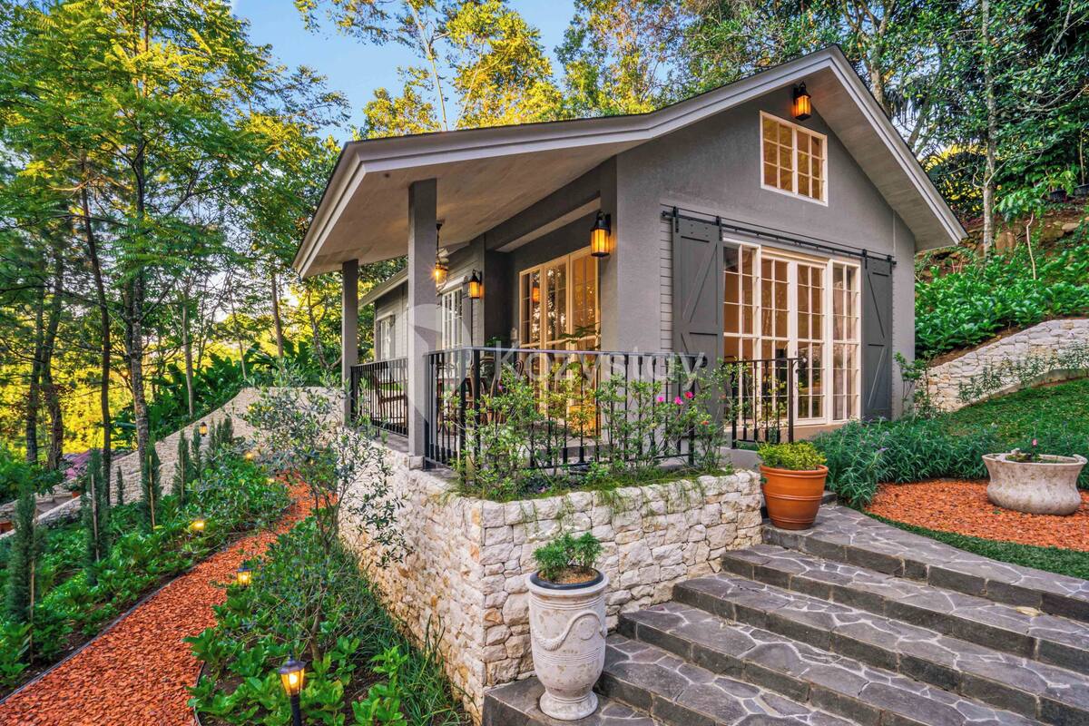 A house with a stone foundation, a covered porch, and a garden with a stone pathway.