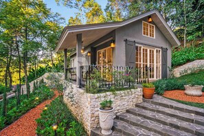 A house with a stone foundation, a covered porch, and a garden with a stone pathway. - Taman Wisata Bougenville by Kozystay (Banjaran)