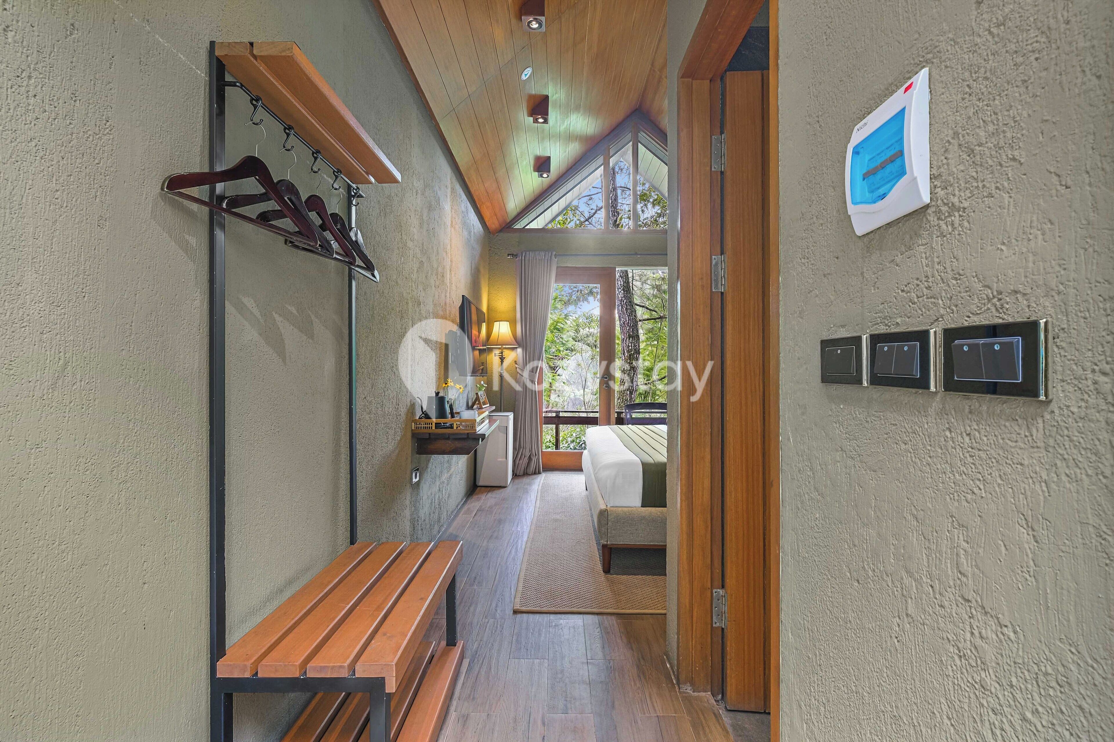 A hallway with a wooden bench, coat rack, and a small table with a lamp.