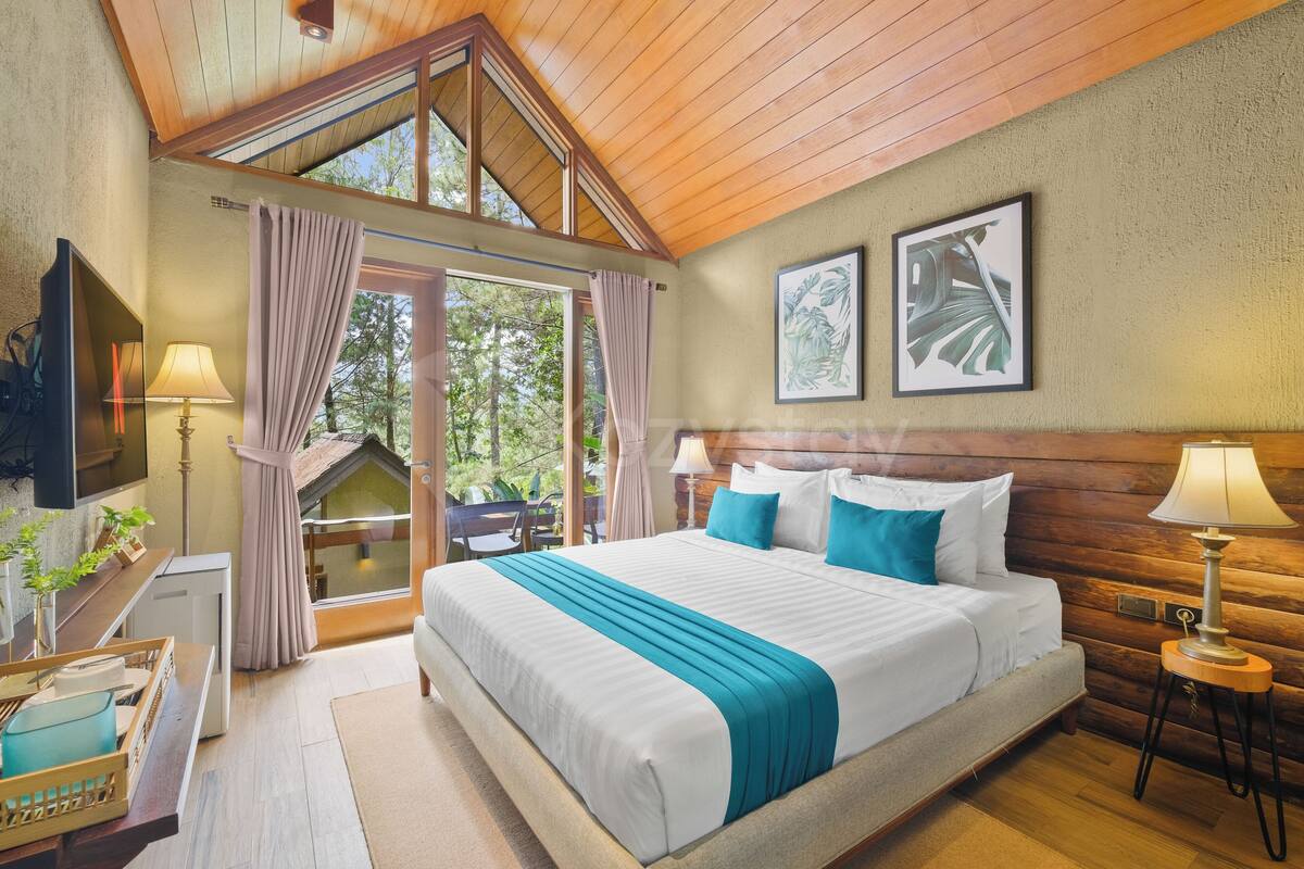 A bedroom with a large bed, wooden ceiling, and a view of the outdoors.