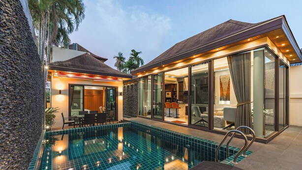 A modern house with a swimming pool, large glass doors, and a well-lit interior. - PoolVilla Jacuzzi & Mountain View V232 (Rawai)