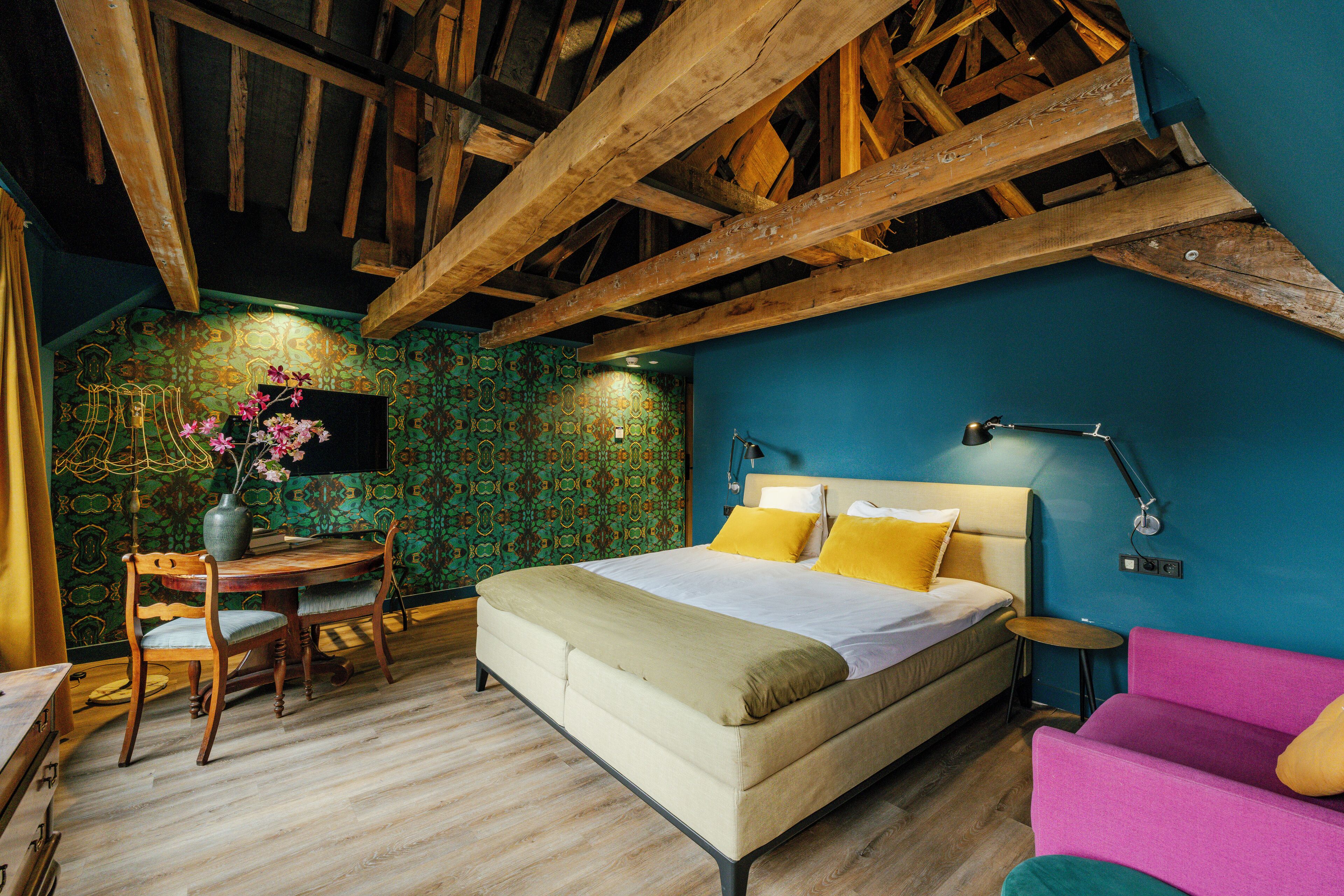 Une chambre à coucher avec un lit, un bureau, une chaise, une petite table et un téléviseur fixé au mur.