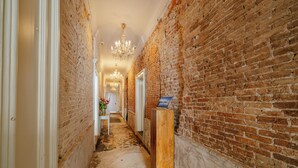 A narrow hallway with exposed brick walls and a wooden floor. - Hotel 1635 (Haarlem)