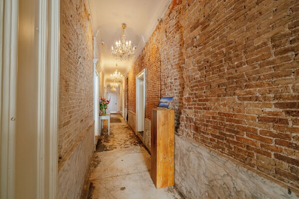A narrow hallway with exposed brick walls and a wooden floor.