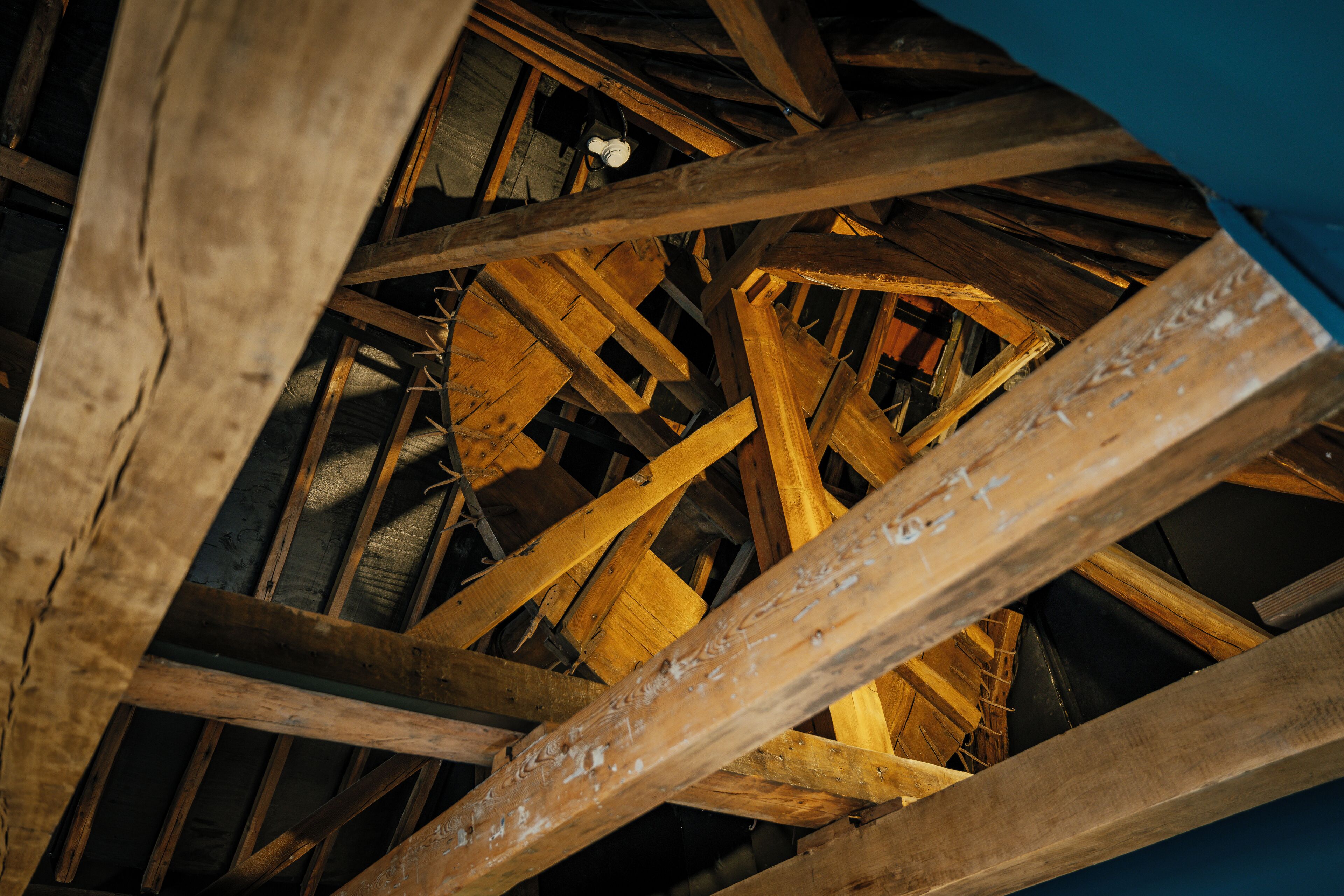 A wooden ceiling structure with beams and a visible light fixture.