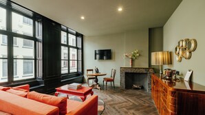A modern living room with a sofa, a coffee table, a fireplace, and a TV mounted on the wall. - Hotel 1635 (Haarlem)