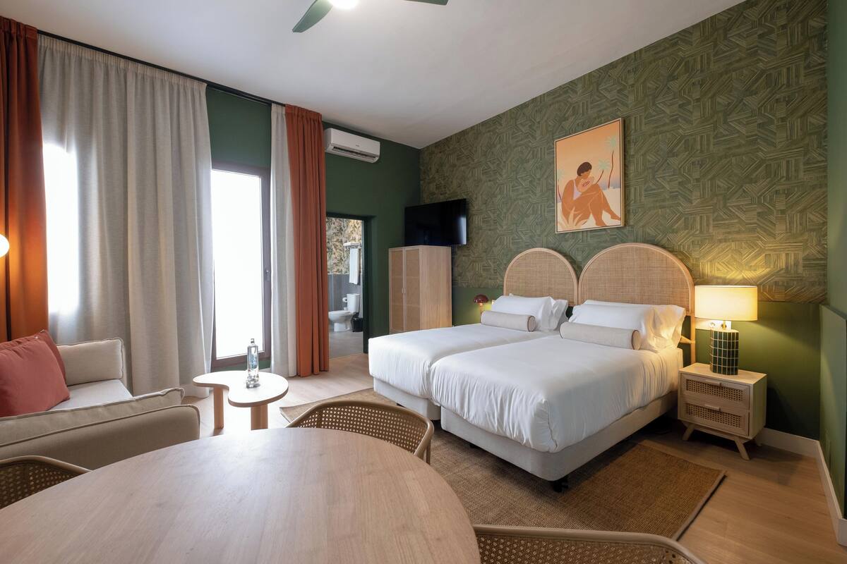 Une chambre d’hôtel avec deux lits, un canapé, une table à manger et un téléviseur.