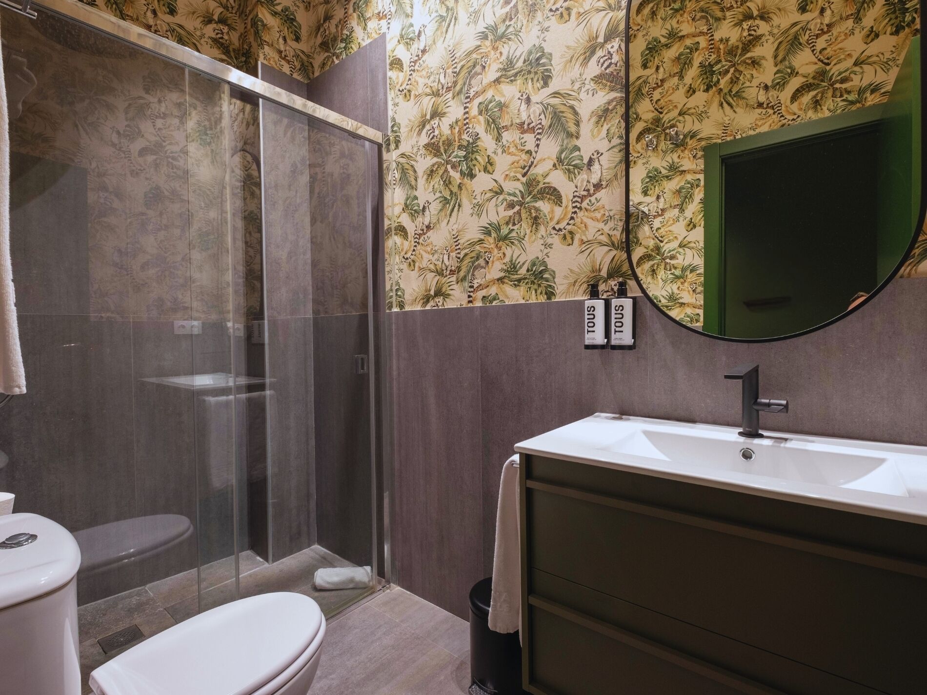 A bathroom with a shower, toilet, sink, and a mirror.