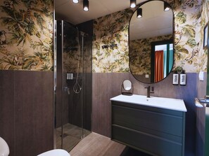 Une salle de bain avec une douche à parois de verre, un meuble-lavabo avec un miroir et des toilettes.