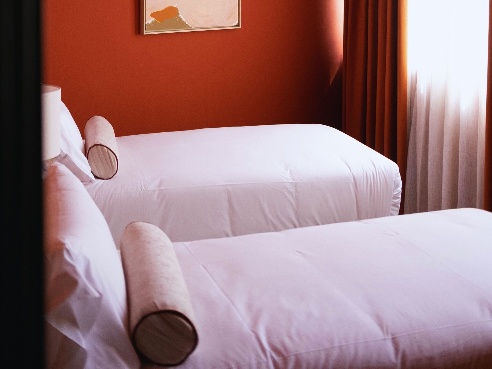 Deux lits simples avec du linge de lit blanc et des têtes de lit en bois dans une chambre d’hôtel.