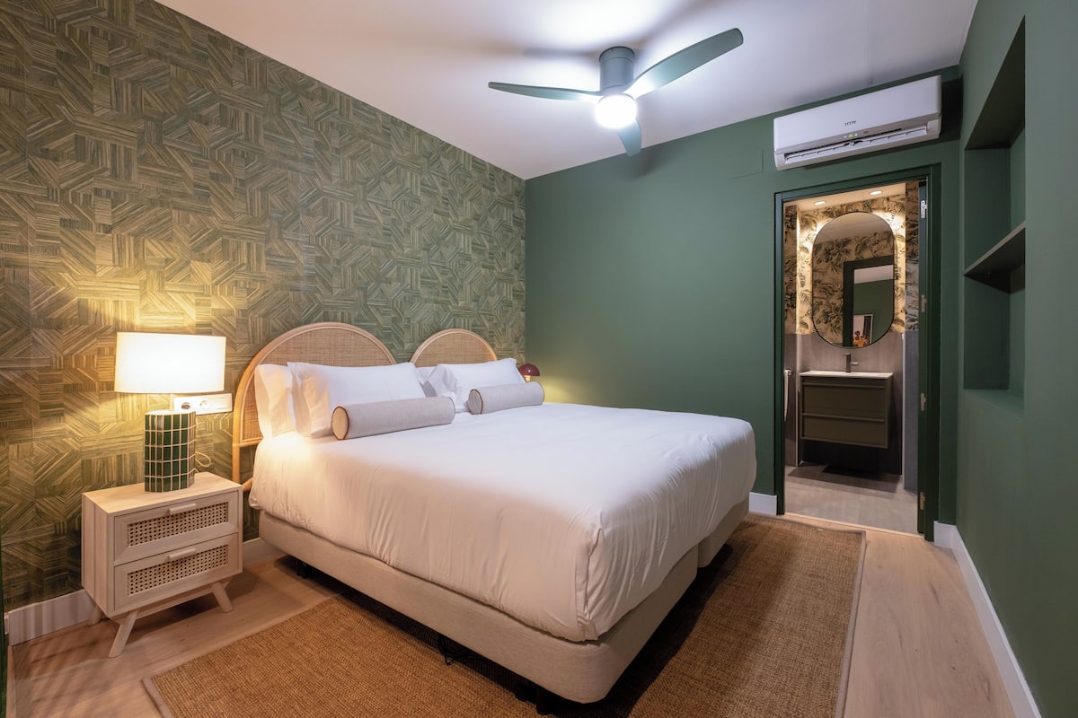 Une chambre à coucher bien rangée, avec un lit, une lampe de chevet et un ventilateur de plafond.