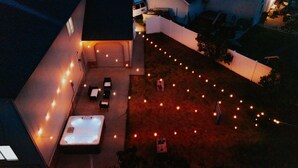 An outdoor patio area with a hot tub, string lights, and outdoor furniture.