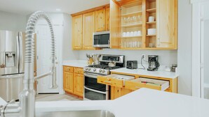 A modern kitchen with wooden cabinets, stainless steel appliances, and a white countertop.