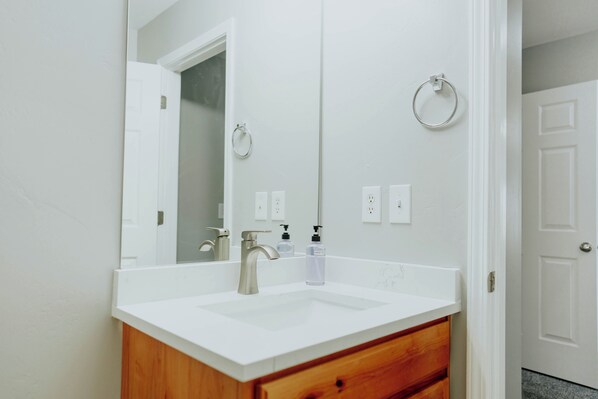 A bathroom with a white sink, wooden vanity, and a large mirror. - 7BR Retreat • Sleeps 25 • Near Ski & Downtown SLC (West Jordan)