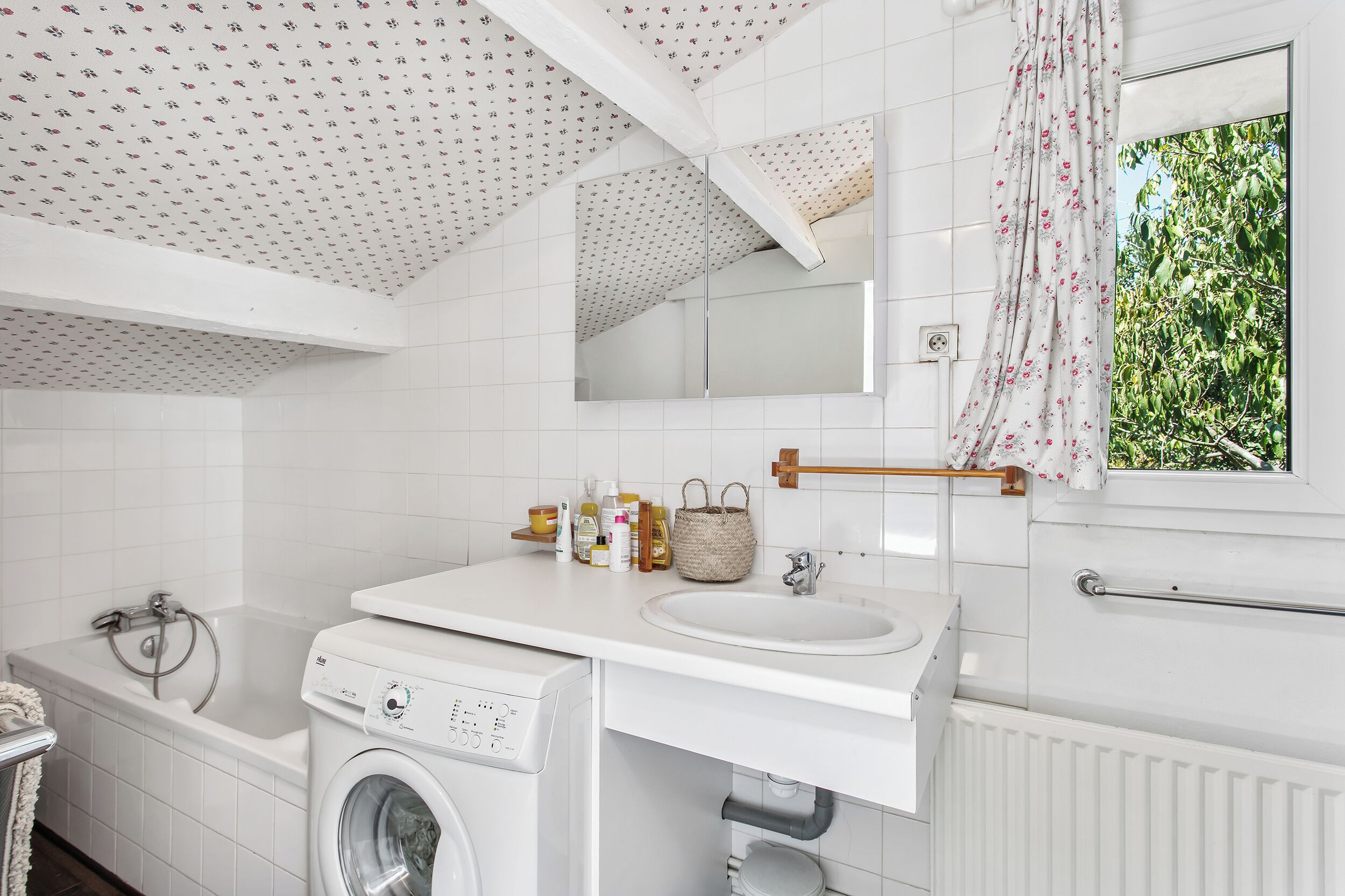 Un bagno moderno con lavatrice, lavandino e uno specchio grande.
