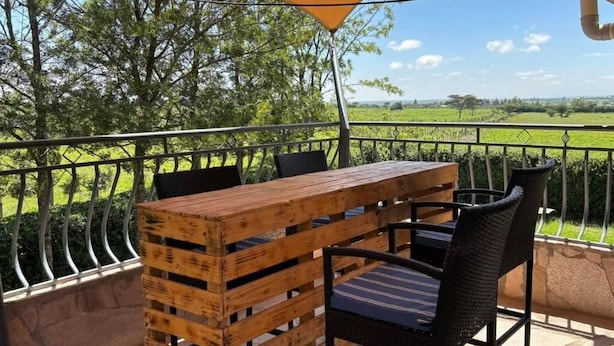 Una mesa y sillas de madera en un balcón con vistas a un paisaje verde.