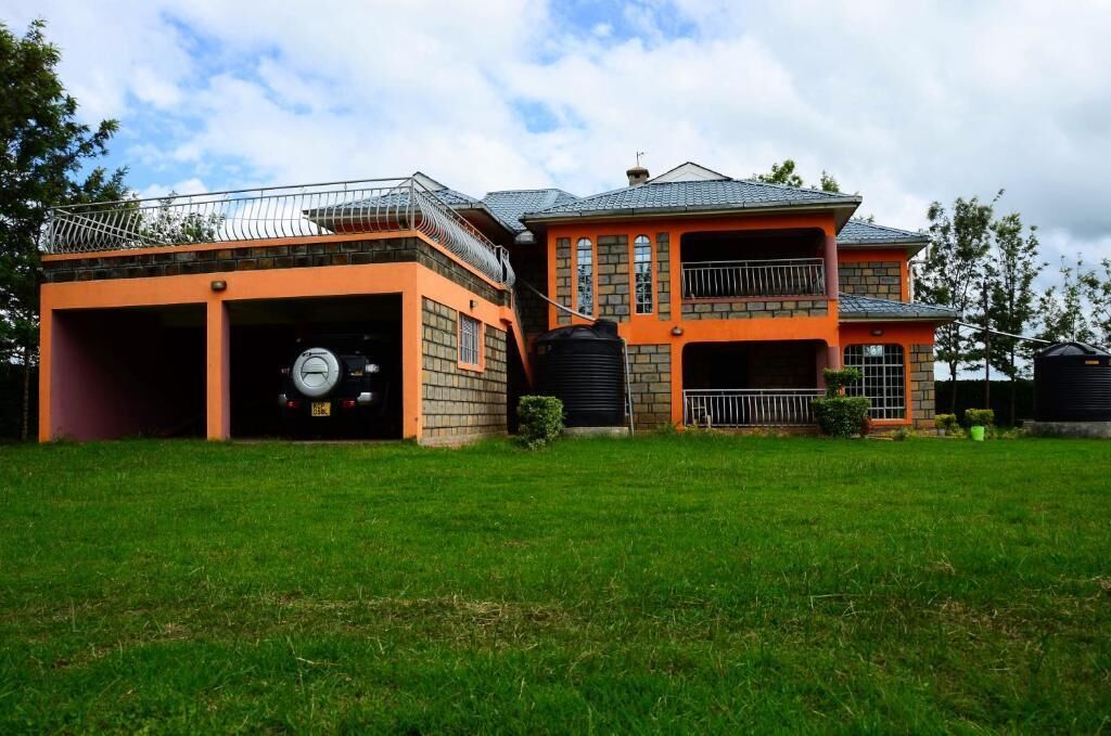 A large, two-story house with a garage, a water tank, and a well-maintained lawn.