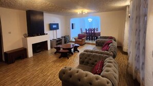 Un salón amplio con chimenea, televisor y un ventanal grande.